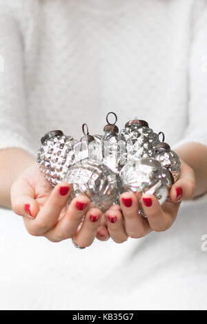 Frau mit Präsentation vintage silver Weihnachtsverzierungen beim Tragen der weißen, klassischen, eleganten, Porträt und Landschaft mit Raum für Kopie Stockfoto