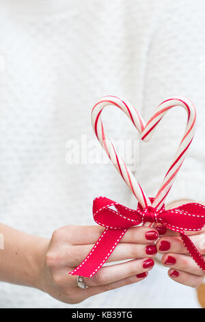 Frau mit frohe Weihnachten Zuckerstangen und einen roten Bogen in einem weißen Pullover vor einem Hintergrund mit Raum für Kopie Stockfoto