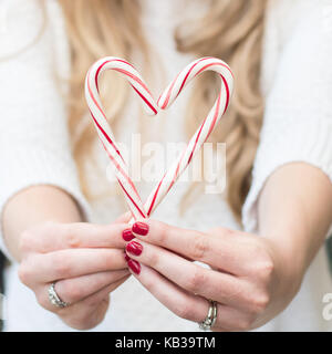 Frau mit frohe Weihnachten Zuckerstangen und einen roten Bogen in einem weißen Pullover vor einem Hintergrund mit Raum für Kopie Stockfoto