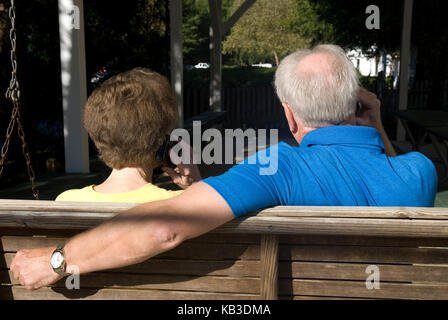 Kaukasisches Senior-Paar (60-70) im Gange, während sie auf dem Handy im Apartment-Komplex, USA, sprachen Stockfoto