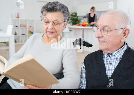 Schöne alte Paar ist ein Buch lesen und lächelnd Stockfoto
