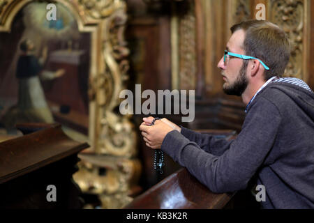 Junger Mann mit Brille und Bart in einer Kirche beten Stockfoto
