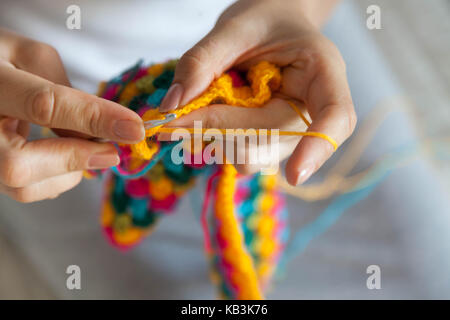 Eine Frau strickt ein farbiges Tuch. Die Hände schließen. Stockfoto