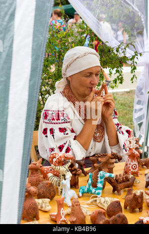 Adygea, Russland - 19 August 2017: Frau spielt Musik auf einem Ton Pfeifen im Shop mit Lehm Souvenirs und Spielzeug auf dem Festival von Käse Adyghe in Ady Stockfoto