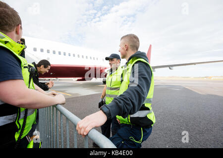 Bodenpersonal der Kommunikation mittels Zaun gegen kommerzielle Flugzeug am Flughafen Stockfoto