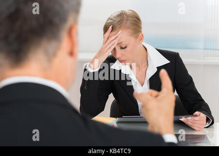 Nahaufnahme der Unternehmer Streiten für junge geschäftsfrau am Schreibtisch Stockfoto