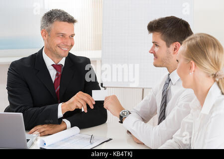 Männliche Berater geben Visitenkarte zu junges Paar im Büro Stockfoto