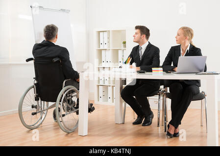 Behinderte ältere Unternehmer zu erklären, seine Kollegen im Büro Stockfoto