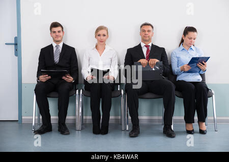 Gruppe von Geschäftsleuten mit Dateien auf Lehrstuhl für das Interview Stockfoto