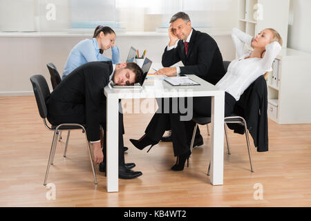 Geschäftsleute, die sich beim Sitzen am Schreibtisch im Büro langweilen Stockfoto