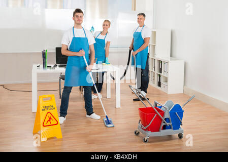 Reiniger Team in Uniform Reinigung Holzboden im Büro Stockfoto