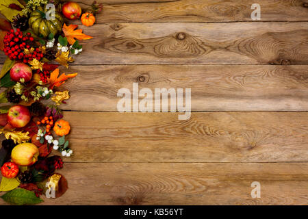 Herbst Hintergrund mit Grenze der Kürbisse, Äpfel, Vogelbeeren und hinterlässt auf der linken Seite des rustikalen Holztisch. Thanksgiving Begrüßung mit Herbst s Stockfoto