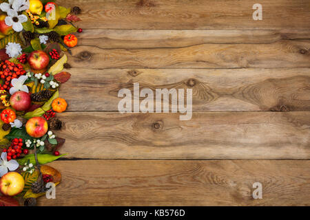 Thanksgiving oder fallen Gruß Hintergrund mit Grenze der Kürbisse, Äpfel, Herbst Blätter und weiße Blumen auf der linken Seite des rustikalen Holztisch, cop Stockfoto