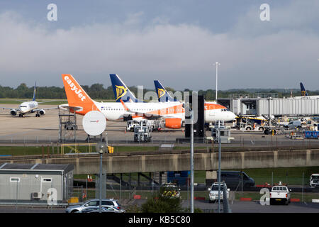 Zwei Ryanair und easyJet Flugzeug ein Flugzeug auf dem Vorfeld des Stansted Airport, Stansted Mountfitchet, Essex, England warten, mit einem anderen Flugzeug Rollens Stockfoto