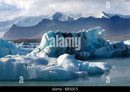 Eisbergen auf der Gletscherlagune Jokulsarlon, mit Berge und Gletscher hinter, South Island, Polargebiete Stockfoto