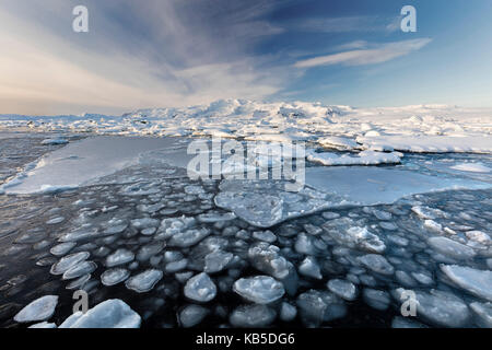 Gefrorene Gletschersee Jökulsárlón Gletscherlagune im Winter mit Eis im Vordergrund und die schneebedeckten Berge in der Ferne, South Island Stockfoto
