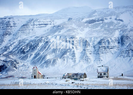 Kirche und abgelegenen Farm gegen schneebedeckte Berge, Winter am Nachmittag auf dem Weg zur Halbinsel Snaefellsnes, Island Stockfoto