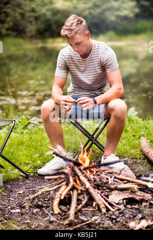 Junge Camping in der Natur, am Lagerfeuer sitzen. Stockfoto