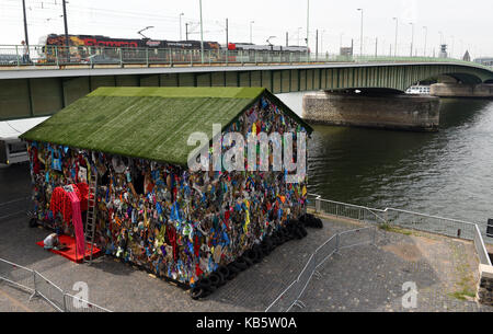 Köln, Deutschland. 30 Aug, 2017. Exklusiv: Der Papierkorb Haus 'Speichern der Welt Hotel", ein Projekt des Künstlers HA Schult, kann am Ufer des Rheins in der Nähe des Deutzer-Rhein Brücke in Köln, Deutschland, 30. August 2017 zu sehen. Die Kunst Projekt besteht aus einem Holz- Haus, das im Müll bedeckt ist, und auch mit "Papierkorb" eingerichtet. Den Papierkorb Haus wird vom 31. August bis 17. September 2017. Credit: Horst Ossinger/dpa/Alamy leben Nachrichten Stockfoto