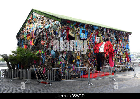 Köln, Deutschland. 30 Aug, 2017. Exklusiv: Der Papierkorb Haus 'Speichern der Welt Hotel", ein Projekt des Künstlers HA Schult, kann am Ufer des Rheins in der Nähe des Deutzer-Rhein Brücke in Köln, Deutschland, 30. August 2017 zu sehen. Die Kunst Projekt besteht aus einem Holz- Haus, das im Müll bedeckt ist, und auch mit "Papierkorb" eingerichtet. Den Papierkorb Haus wird vom 31. August bis 17. September 2017. Credit: Horst Ossinger/dpa/Alamy leben Nachrichten Stockfoto