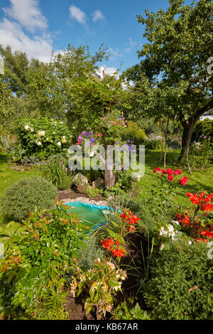 Blumenbeet mit kleinen Teich im Schrebergarten an einem sonnigen Sommertag. Region Kaluga, Russland. Stockfoto