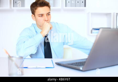 Porträt der jungen nachdenklich Geschäftsmann an seinem Arbeitsplatz im hellen Büro Stockfoto