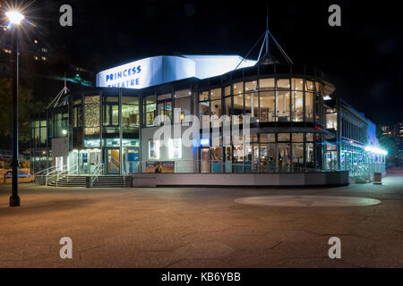 Seite, vorne der Erhöhung von Princess Theatre, Torquay Devon, Großbritannien. In der Nacht, in der Lobby und in der Bar sichtbar und die Strandpromenade an der Seite beleuchtet Stockfoto