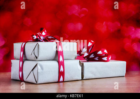 Rustikale Geschenk mit Herz Bänder auf abstrakten Hintergrund. Gegenstand gegen weiche Fenster Beleuchtung und kopieren Raum gefangen. Stockfoto