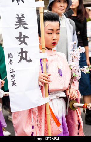 Jährliche Genji Parade an Tada, Japan. Junge Junge, Wandern, verkleidet als Heian-zeit Edelmann in rosa Roben, die Banner. Close Up, kein Auge - Kontakt. Stockfoto