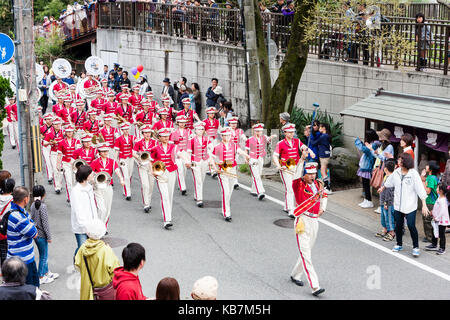 Japan, Tada, jährliche Genji Parade. Blasorchester der Frauen in rosa Tuniken und weißen Kappen, Gang durch die Straße, die sich in der Ausbildung zur Aufnahme von Instrumenten. Stockfoto