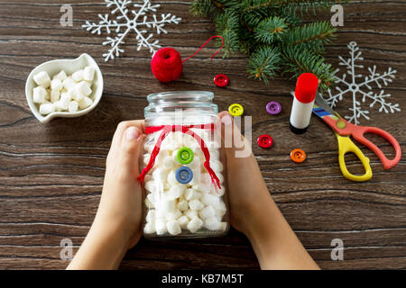 Ein Kind ist ein Weihnachten mit einem Schneemann von Süßigkeiten vorhanden. mit eigenen Händen gemacht. Kunst für Kinder Projekt für Kinder. Handwerk für Kinder. Kopieren Sie Platz für Stockfoto