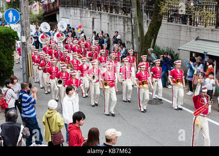 Japan, Tada, jährliche Genji Parade. Blasorchester der Frauen in rosa Tuniken und weißen Kappen, Gang durch die Straße, die sich in der Ausbildung zur Aufnahme von Instrumenten. Stockfoto