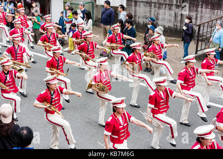 Japan, Tada, jährliche Genji Parade. Blasorchester der Frauen in rosa Tuniken und weißen Kappen, Gang durch die Straße, die sich in der Ausbildung zur Aufnahme von Instrumenten. Stockfoto