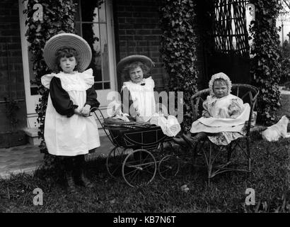 AJAXNETPHOTO. 1890 - 1914 (ca.). Ort unbekannt. - Drei KLEINE MÄDCHEN POSIEREN FÜR DIE KAMERA IN EINEM CARDEN MIT PUPPEN IN EINEM SPIELZEUG KINDERWAGEN UND HUND. Fotograf: unbekannt © DIGITAL IMAGE COPYRIGHT AJAX VINTAGE BILDARCHIV QUELLE: AJAX VINTAGE BILDARCHIV SAMMLUNG REF: AVL 172109 3 Stockfoto