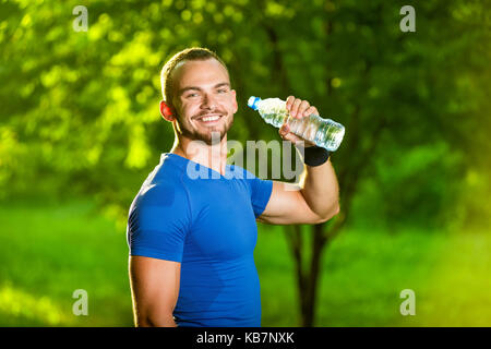 Sportlicher reifen Mann Trinkwasser aus der Flasche Stockfoto