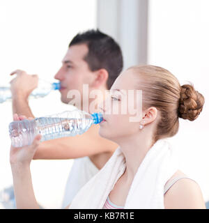 Mann und Frau Trinkwasser nach dem Sport in der Turnhalle Stockfoto