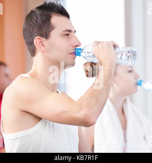 Mann und Frau Trinkwasser nach dem Sport in der Turnhalle Stockfoto