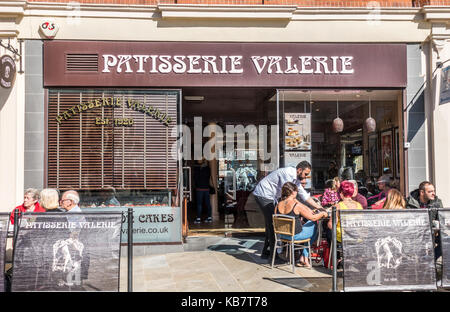 Mann sitzend Kunden im warmen Sonnenschein an Patisserie Valerie Cafe bietet, Cathedral Square, das Stadtzentrum von Peterborough, Cambridgeshire, England, UK. Stockfoto