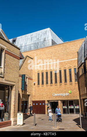 Die Menschen verlassen sonnenbeschienenen Queensgate Shopping Center, vor blauem Himmel, in der Mitte der Stadt Peterborough, Cambridgeshire, England, UK. Stockfoto