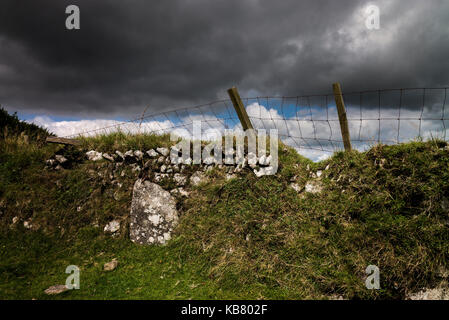 Steinmauer und Fechten mit dunklen Wolken am Bodmin Moor Cornwall GROSSBRITANNIEN Stockfoto