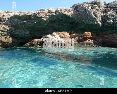 Ein Foto von dem türkisfarbenen kristallklaren Wasser der Blue Lagoon, Malta, mit weißem Sand und einem Felsvorsprung Bogen über das Wasser und blauem Himmel Stockfoto