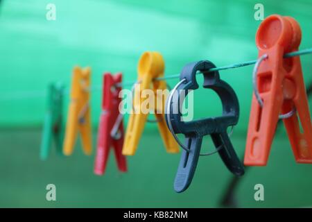 Unterschiedlich geformte bunte Wäscheklammern hängen an der Wäscheleine. Stockfoto