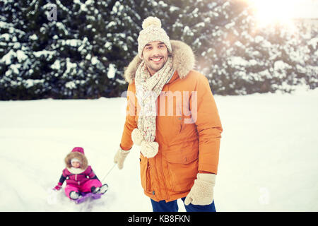 Glückliche Menschen, die wenig Kind auf Schlitten im Winter Stockfoto