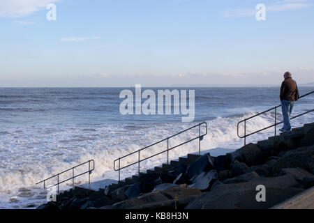 Person auf Stufen, die hinunter zum Strand wie die Flut kommt An Seaton Carew Hartlepool Stockfoto