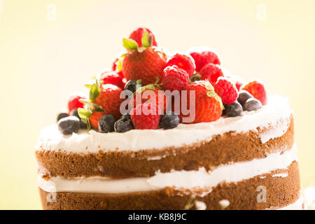 Eine schöne handgemachte Hochzeitstorte liebevoll garniert mit einem bunten Sortiment von Erdbeeren, Himbeeren und Blaubeeren. In der Nähe der Oberseite des Stockfoto