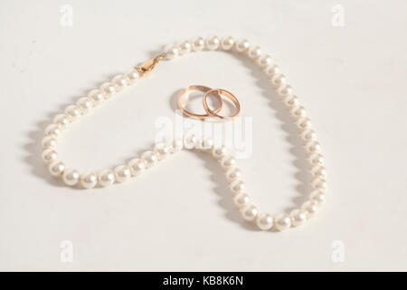 Perlenkette in Herzform ende Trauringe Stockfoto