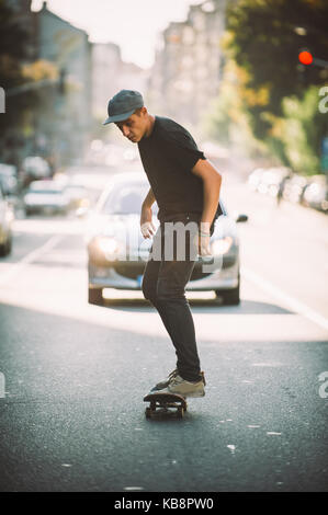 Pro Skate rider ride Skateboard vor dem Auto auf die Stadt Straße Straße durch Staus Stockfoto