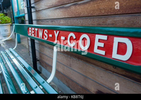 Name des Bahnhofs auf einer Holzbank am Bahnhofsplatz in Betws-y-Coed, einer beliebten Touristenstadt für Outdoor-Aktivitäten. Stockfoto