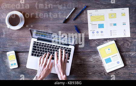 Webdesigner skizzieren responsive Website wireframe Mockups mit Laptops, Smartphones und Tablet Computer auf Holztisch, UI und UX front end Dev Stockfoto