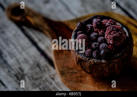 Gefrorene Heidelbeeren im Ton Schüssel mit dunklem Hintergrund Nahaufnahme Stockfoto